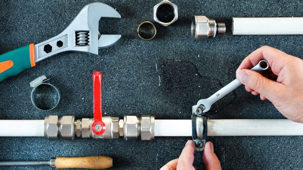 Plumber repairing a pipe valve with an adjustable wrench in Casselberry
