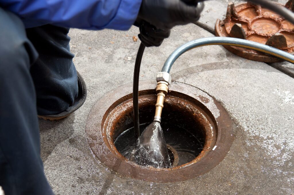 Plumber hydro jetting a sewer line through a manhole in Casselberry
