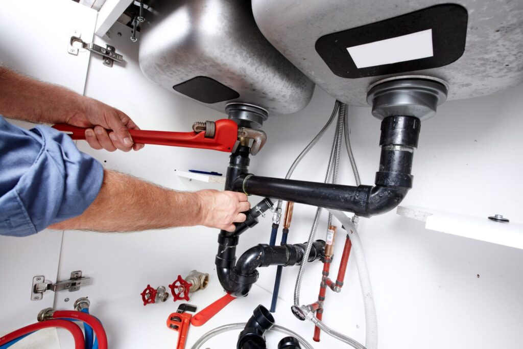 Plumber repairing drain pipes beneath a kitchen sink in Casselberry