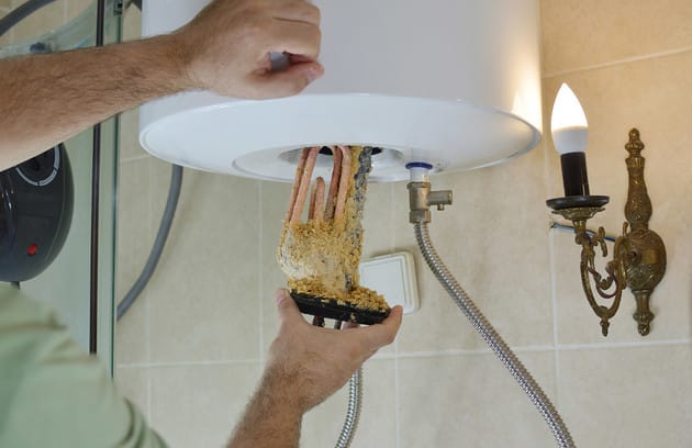 Technician removing mineral buildup from a water heater in Casselberry